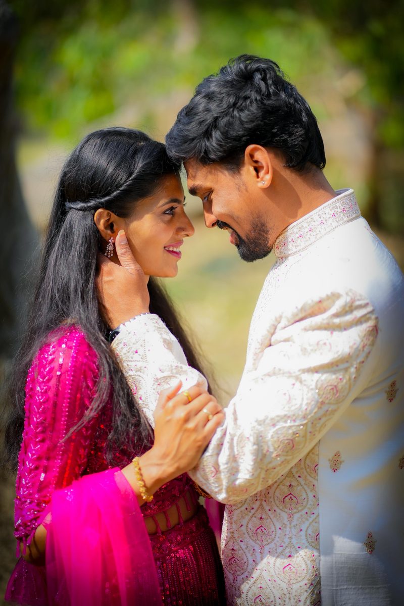 Couple in pink saree and ivory sherwani, foreheads close, in golden light