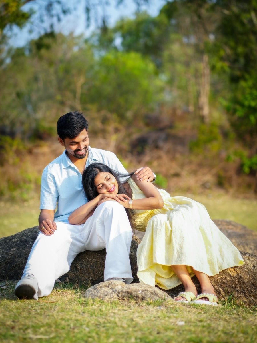 Couple seated on a rock in the outdoors, her head resting on his shoulder